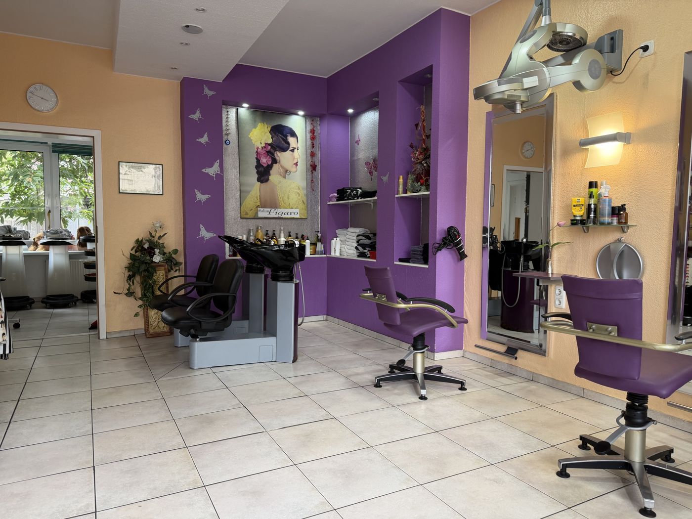 Blick in den Salon mit lila Wänden, Waschplatz und Frisierplätzen